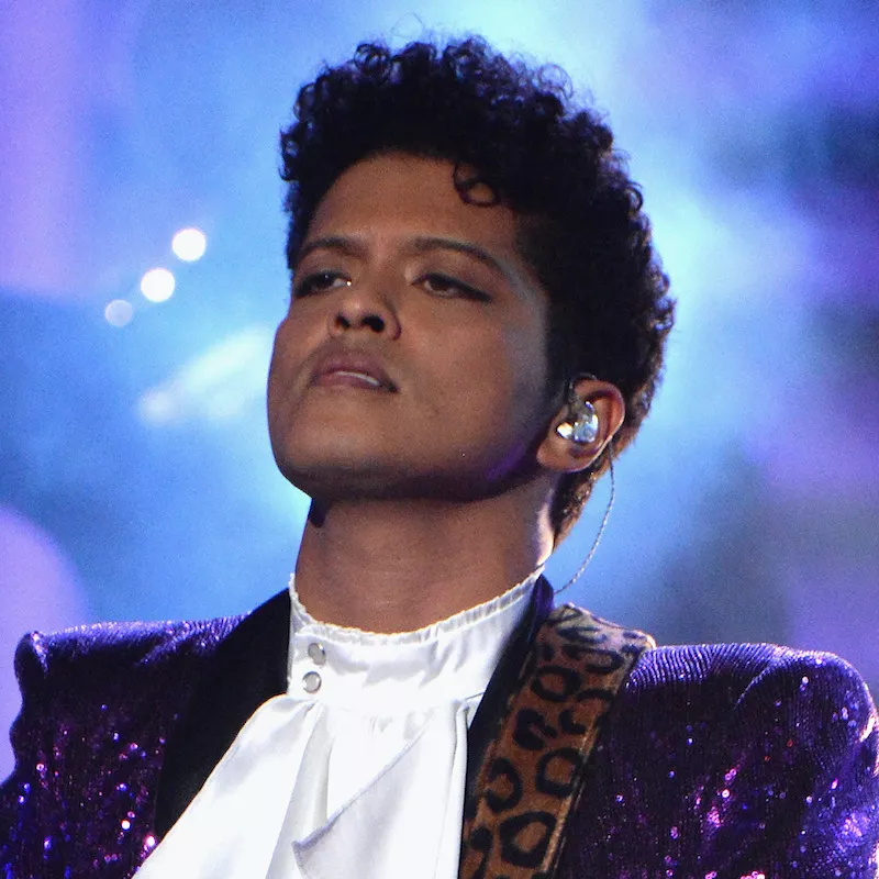 Bruno Mars wears a Jheri curl hairstyle and purple Prince jacket