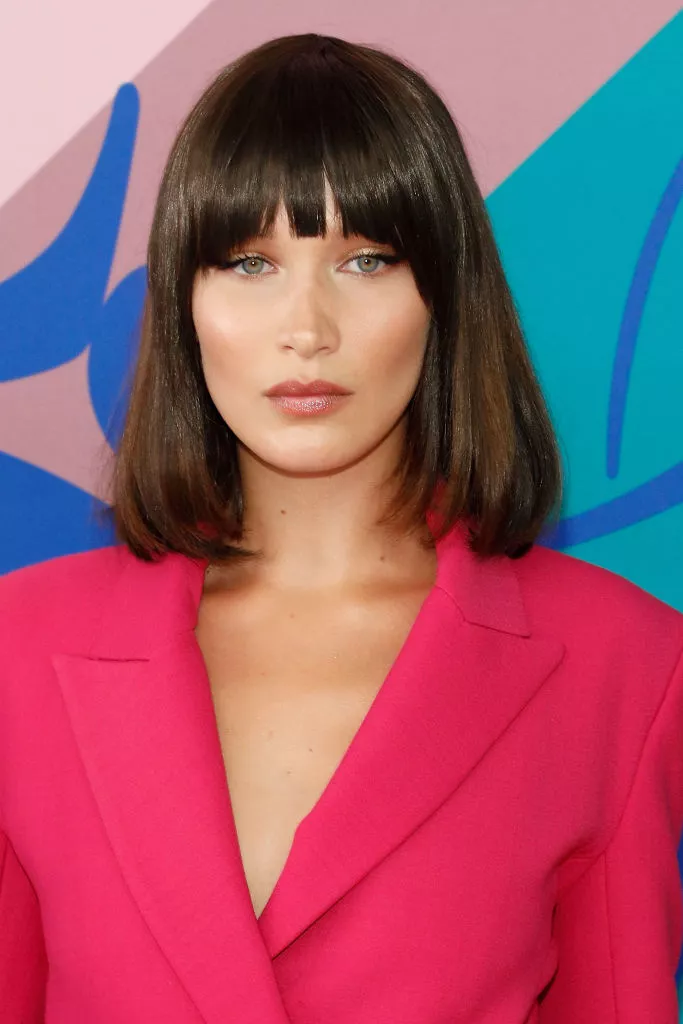 Bella Hadid with bangs in a pink blazer.