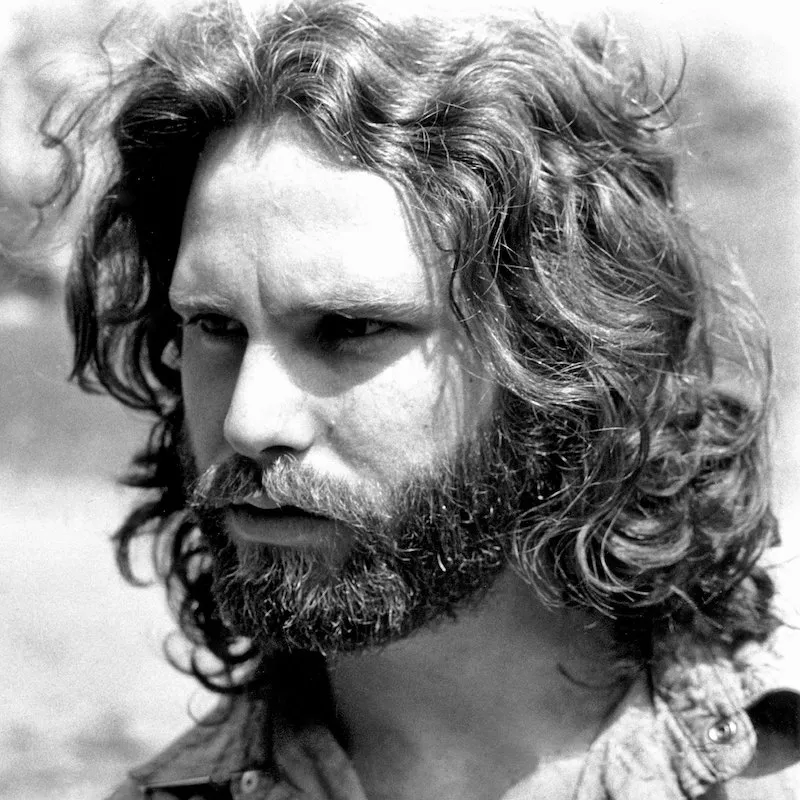 Jim Morrison wears his signature wavy hair and beard