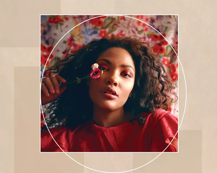 Black Woman with Natural Hair Against Floral Background Holding a Flower with Bright Pink Eyeshadow 