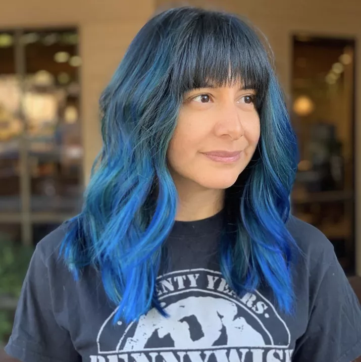 Woman with blue ombre hairstyle and blunt bangs
