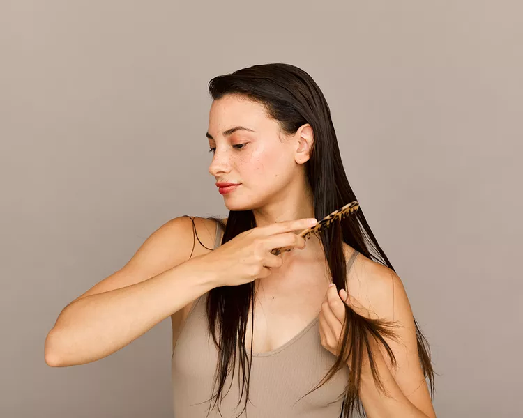 Woman in a neutral top combing wet hair