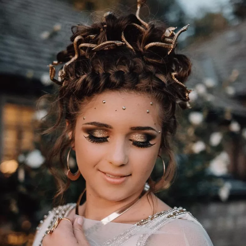 Woman with Medusa Halloween costume featuring bronze eyeshadow and braided updo with gold snakes