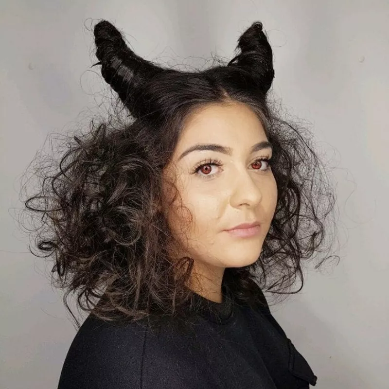 Woman with Maleficent-inspired curly hairstyle with horns and red eye contacts