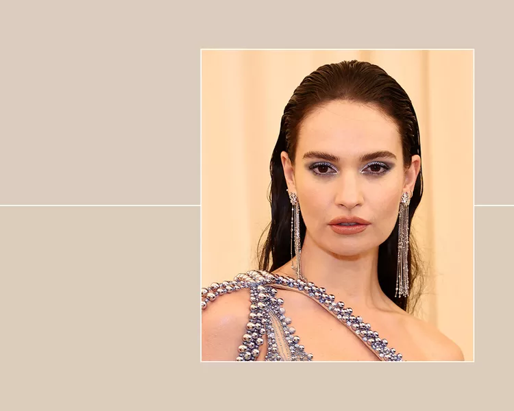 The actor Lily James with slicked back hair wearing a one shoulder dress