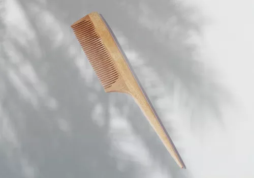 Japanese wooden beard comb with tail on gray palm shadow background