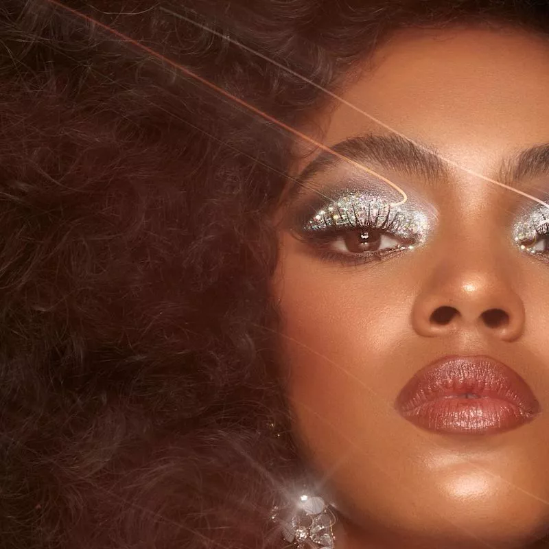 Model with curly disco-inspired hair and silver diamond eyeshadow