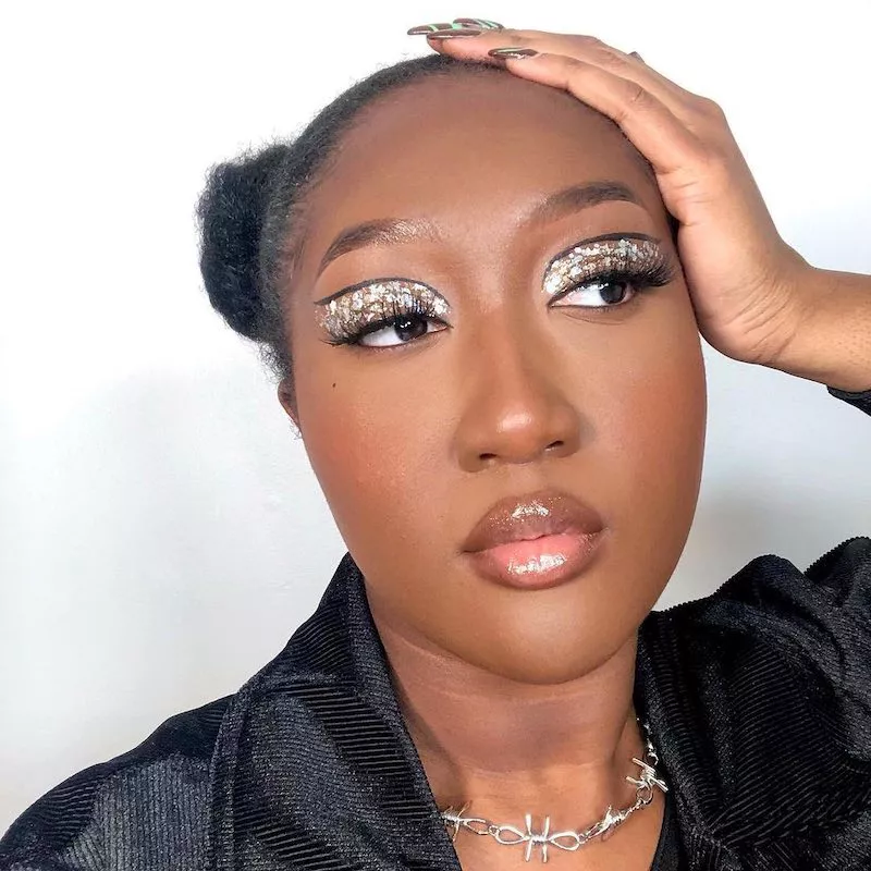 Woman wears silver glitter eye makeup with thin black cut crease