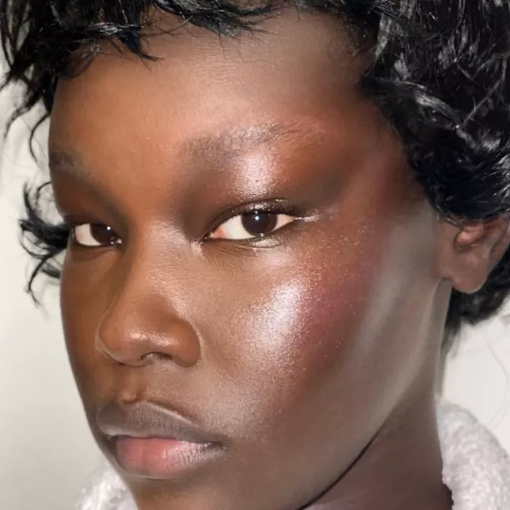 Model with neutral, glowy makeup look featuring pink-toned blush