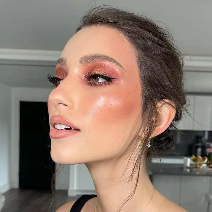 Model wears sunset gradient eyeshadow and rust-toned blush