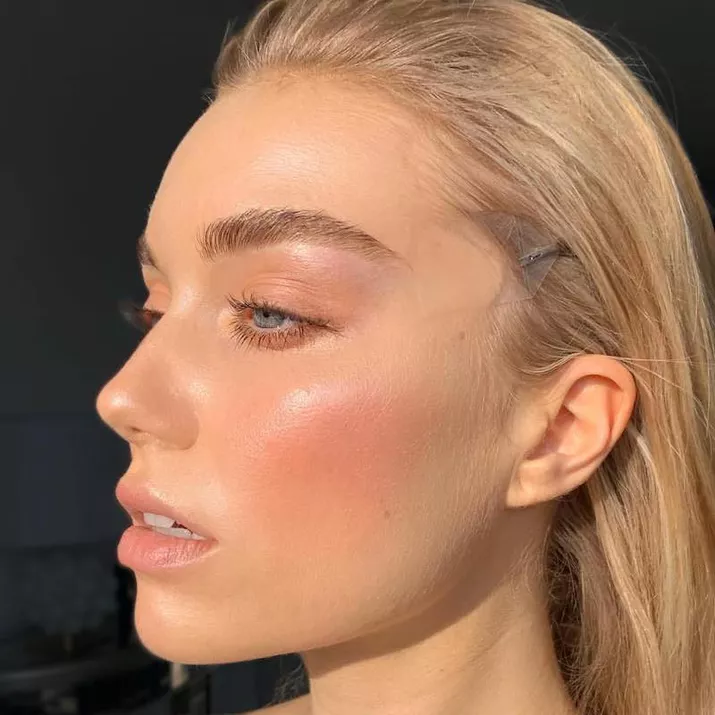 Model wears a fresh makeup look with peach-toned blush and eyeshadow