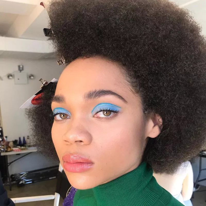 Model with Afro hairstyle wears bright blue eyeshadow and floating liner at crease