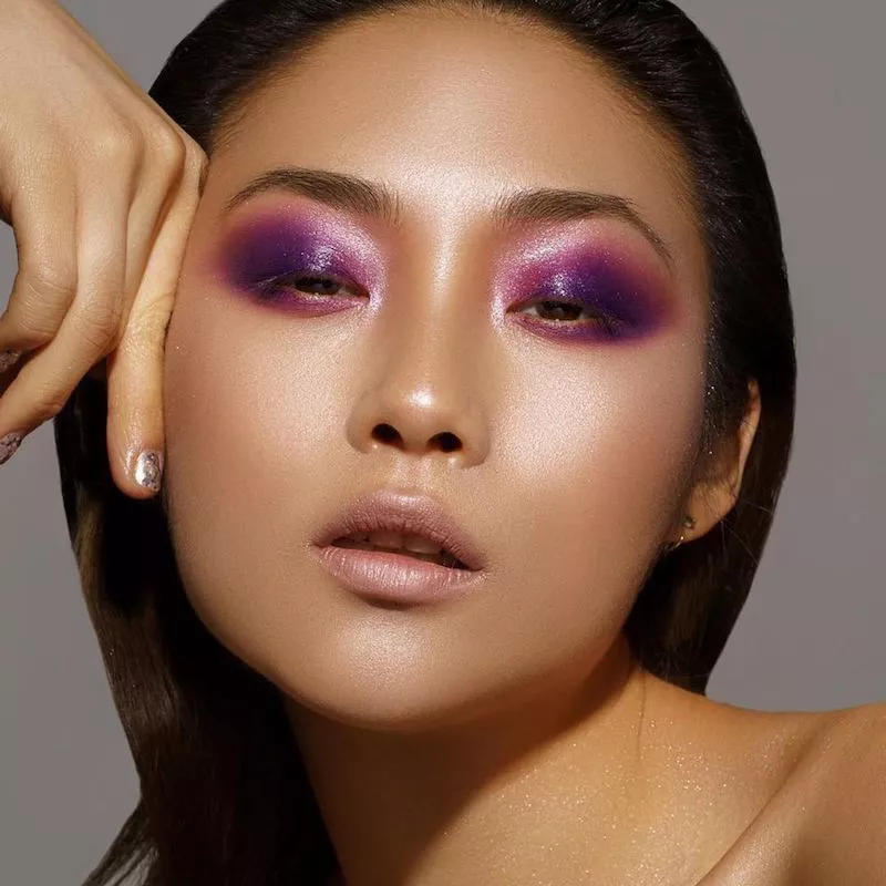 Model with vibrant purple smoky eyeshadow and glowing skin