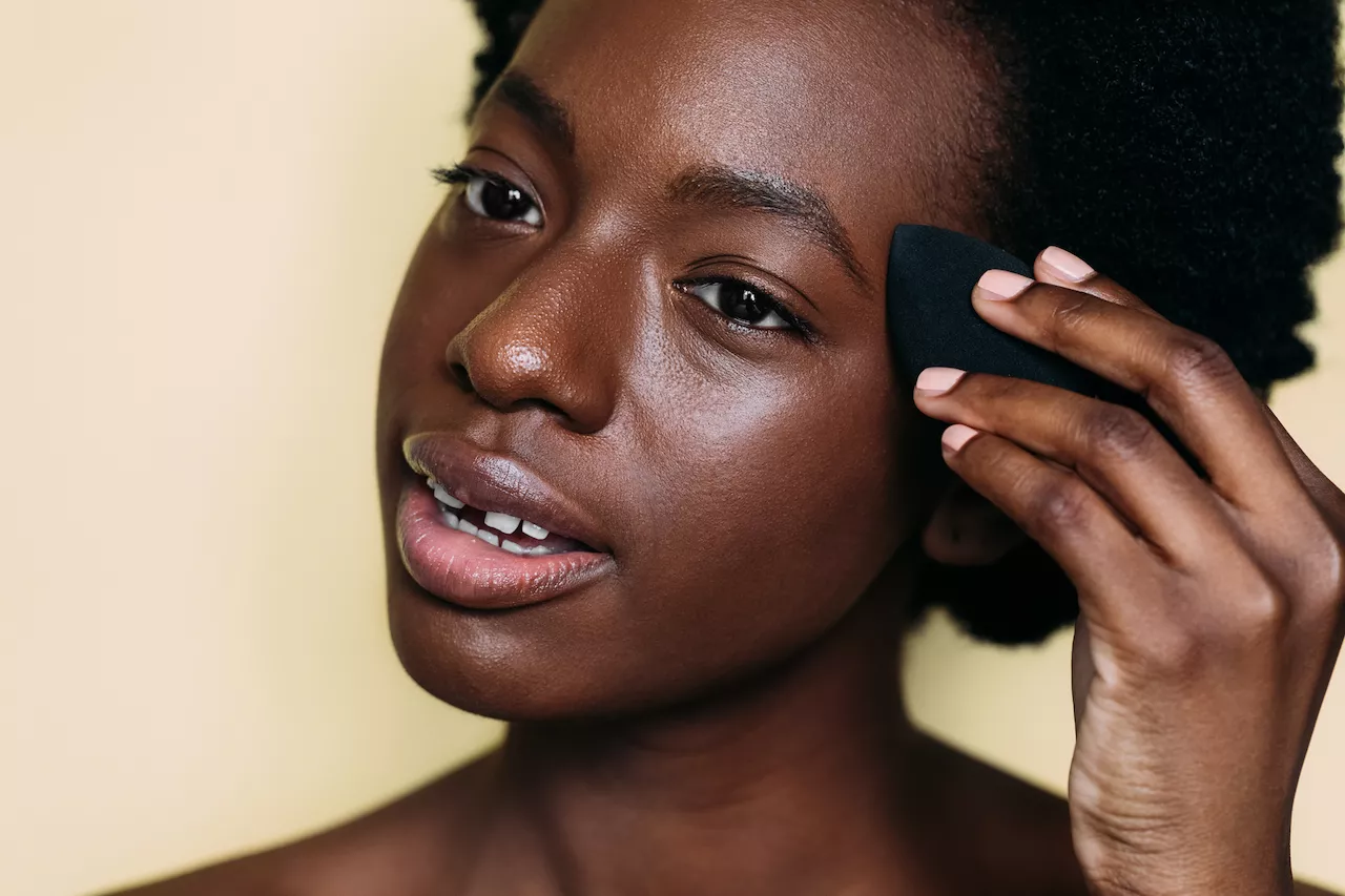 Woman applying foundation with a blending sponge.