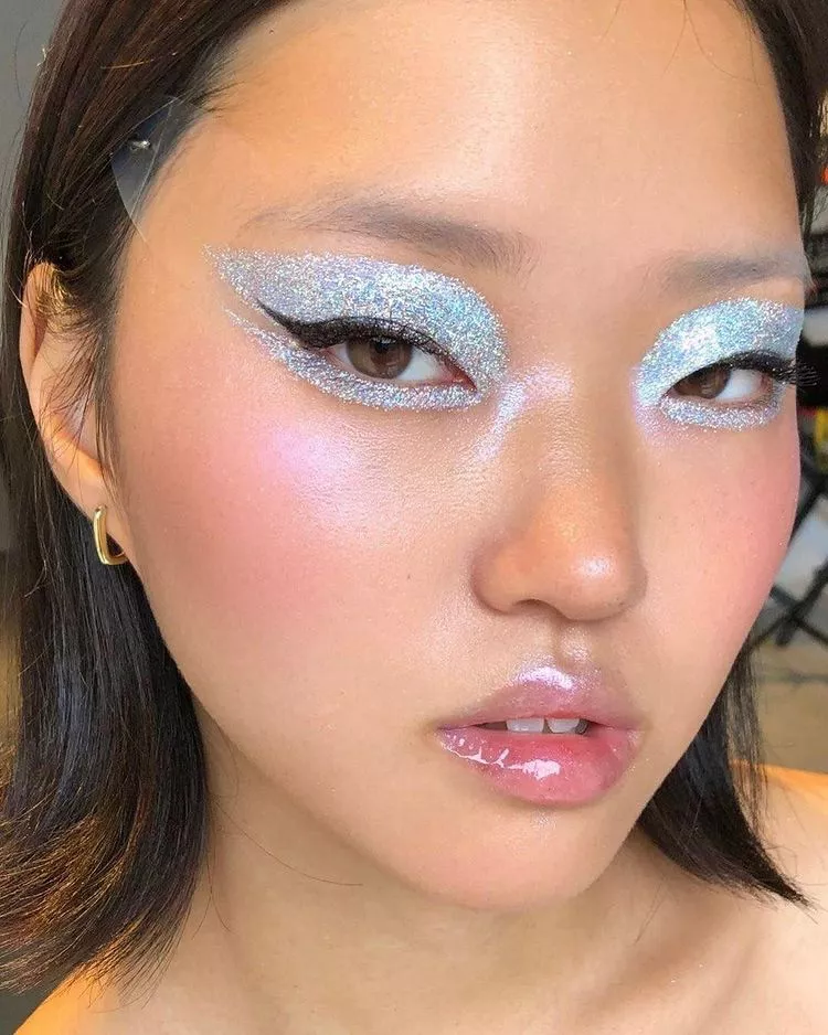 Model wearing glitter eye with winged liner and glossy lips