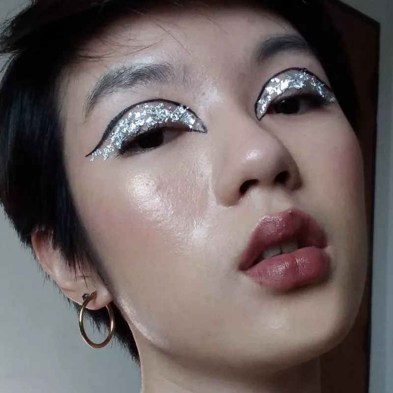 Creator wears silver glitter eyeshadow with black graphic eyeliner