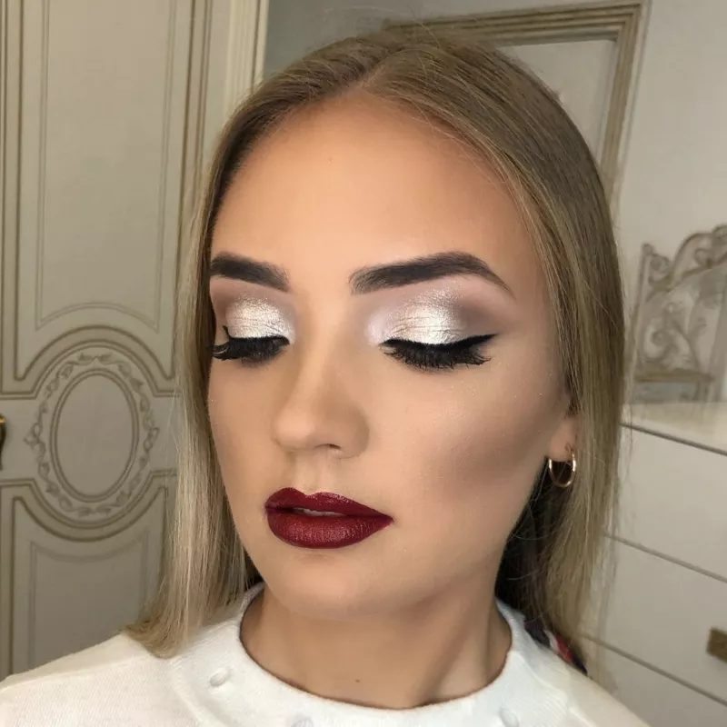 Woman with silver eyeshadow, winged liner, and oxblood red lipstick