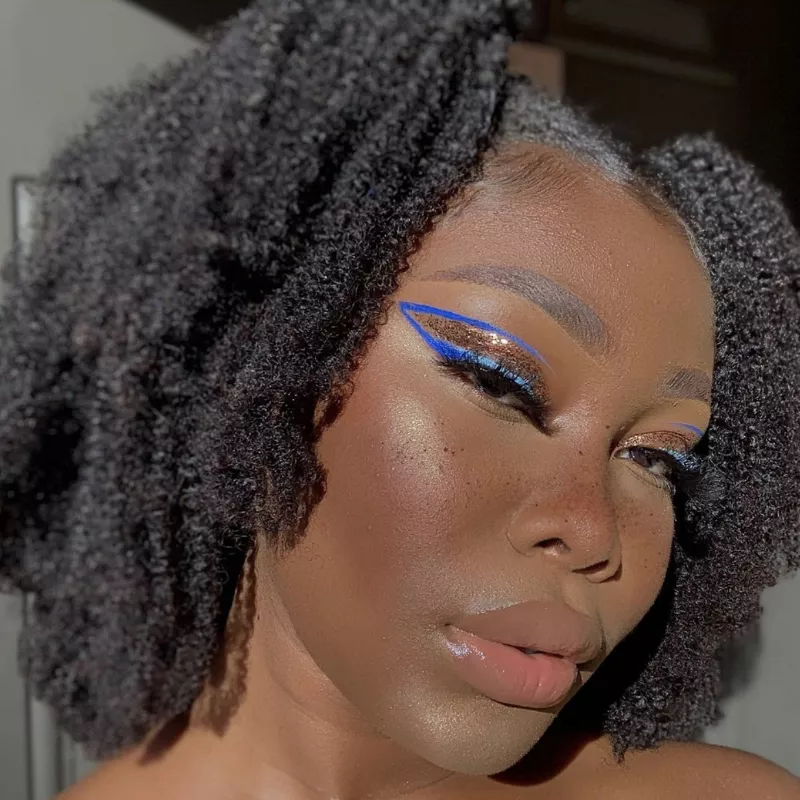 Woman with cobalt blue graphic eyeliner filled with bronze glitter
