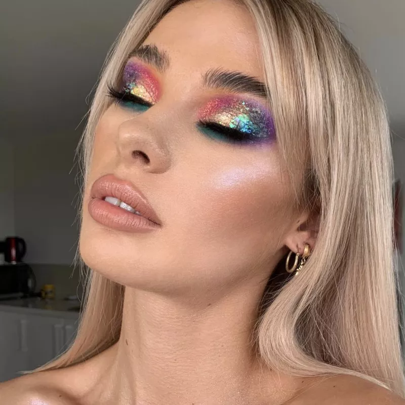 Model wears rainbow gradient eye makeup with glitter