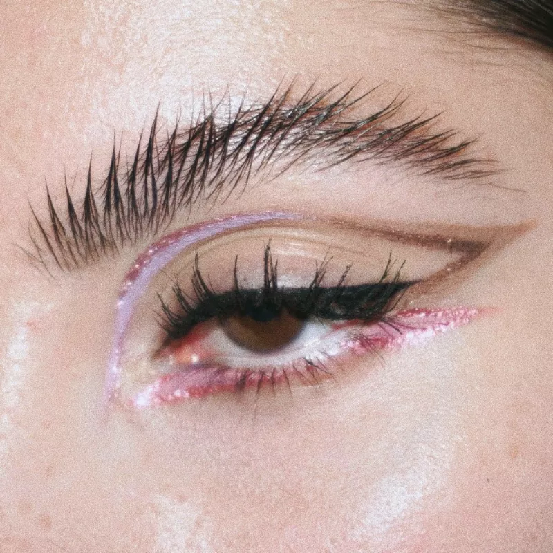 Woman wears multicolored pink and brown graphic eyeliner with glitter