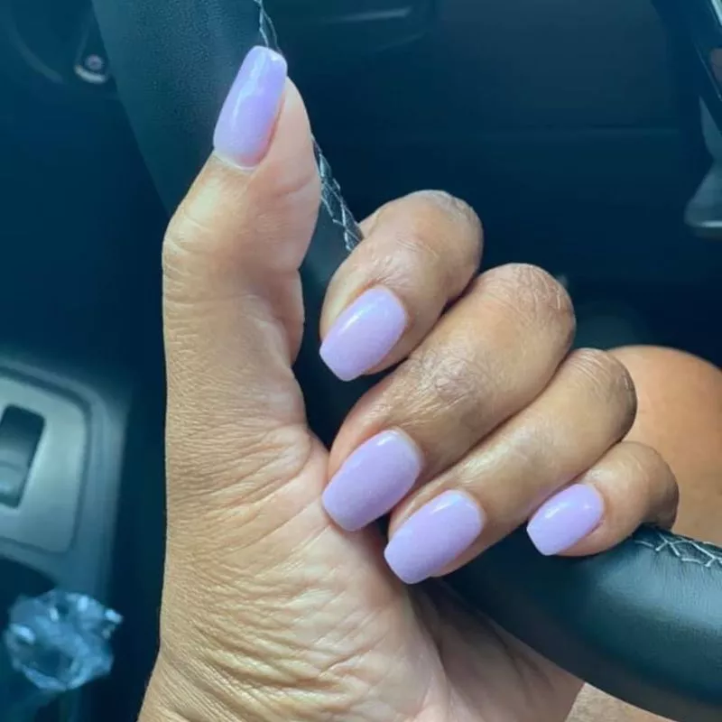 Lavender dip powder nails on hand holding steering wheel