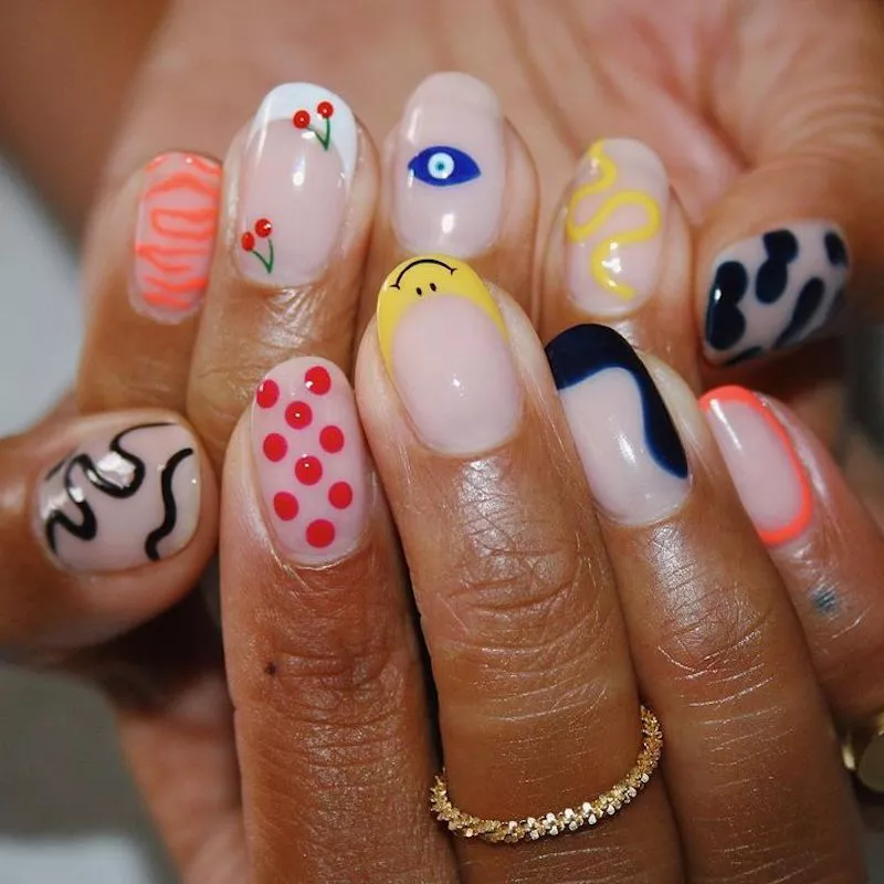 Mixed-design manicure with smiley French, evil eye, squiggles, cherries, and more