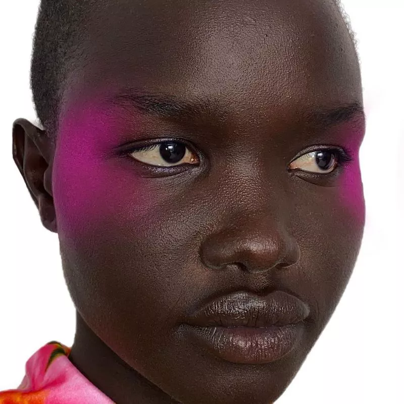 Model with bold, abstract hot pink eyeshadow look on outer temples