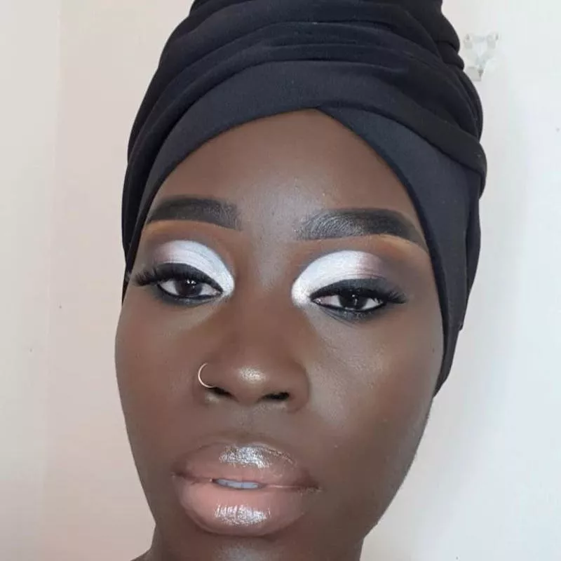 Woman with silver and black eyeshadow, head wrap, and glossy lips