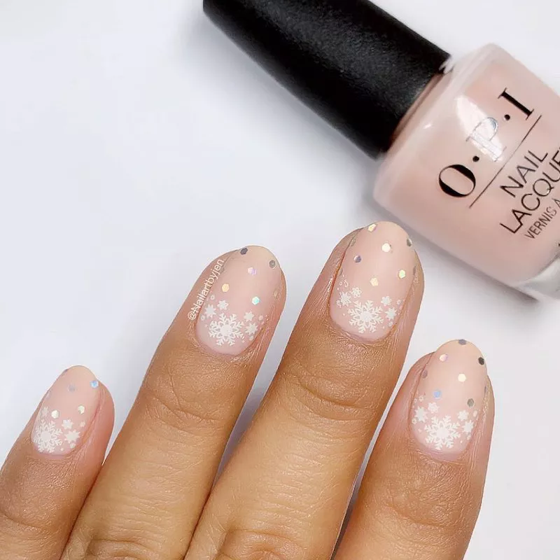 Light pink manicure with snowflake designs and silver dots