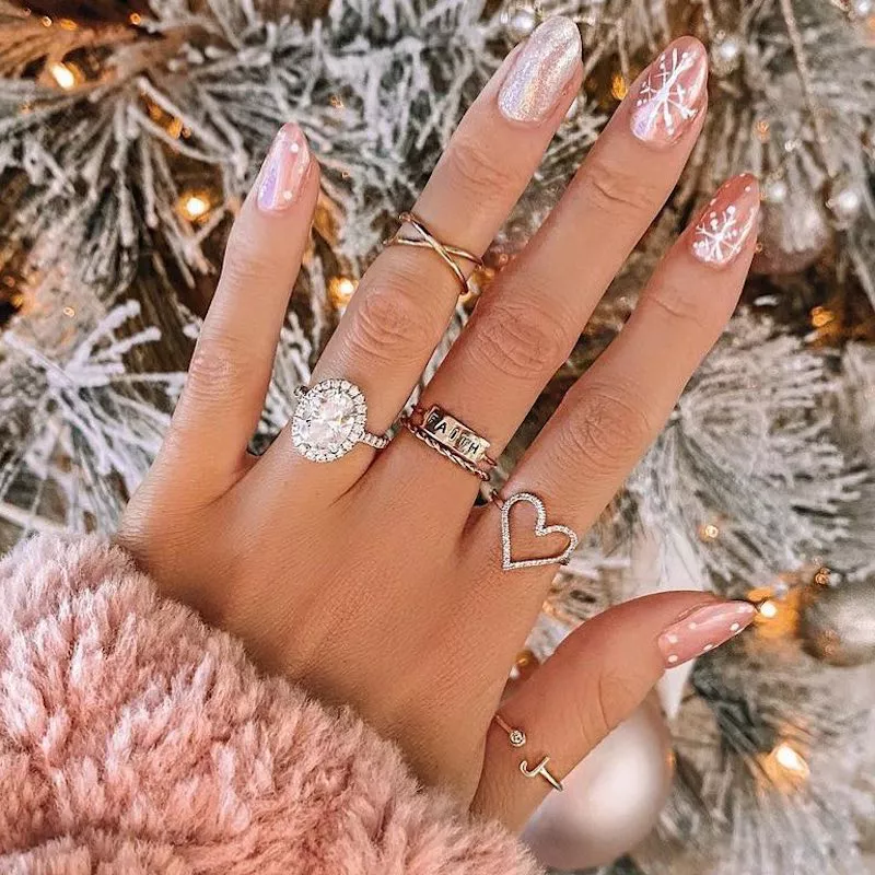 Rose gold manicure with white snowflake designs and silver sparkle accent nail