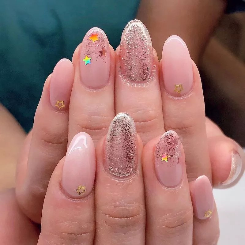Glitter ombre nails on peachy nude background with stars