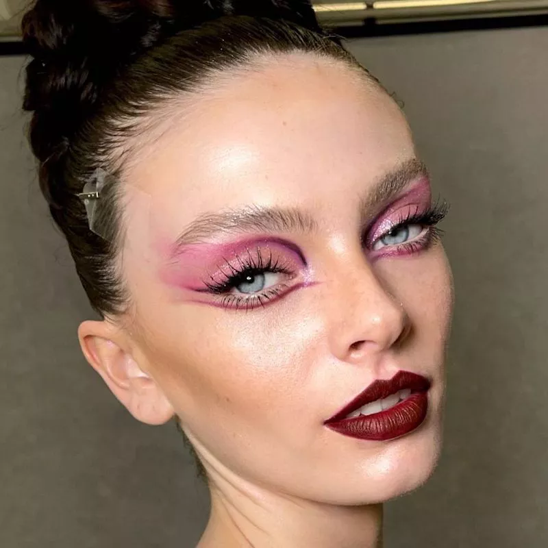 Model with abstract pink and purple eye makeup and burgundy lipstick