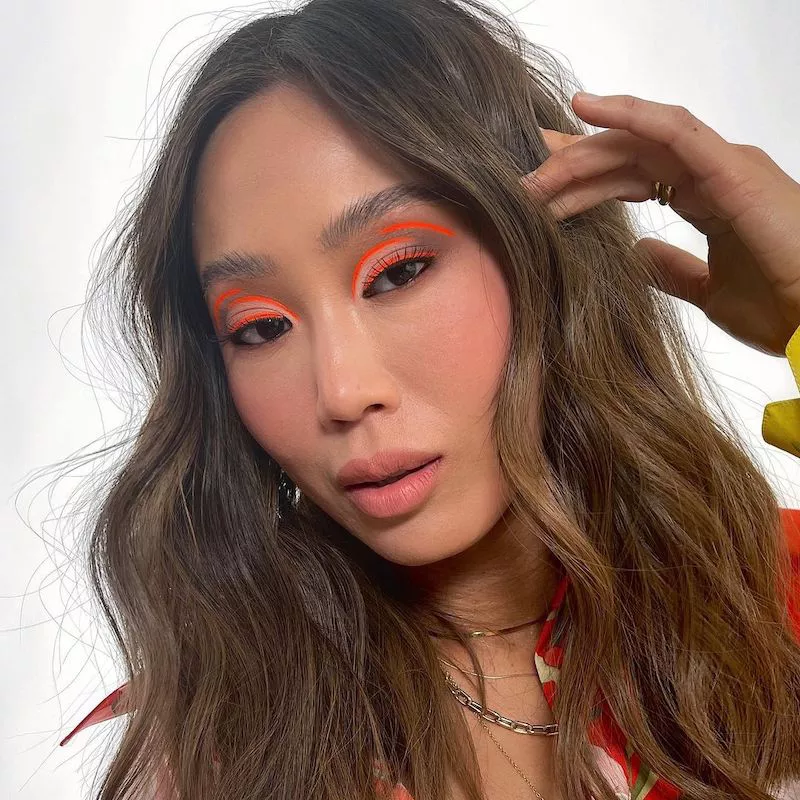 Aimee Song wears a neon orange graphic floating eyeliner look