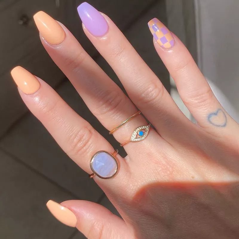 Pastel peach manicure with pastel purple accents and checkerboard