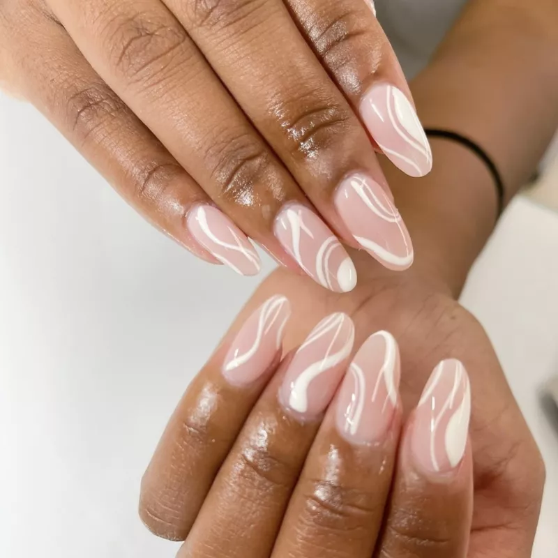 Rose-toned neutral nails with white swirl designs
