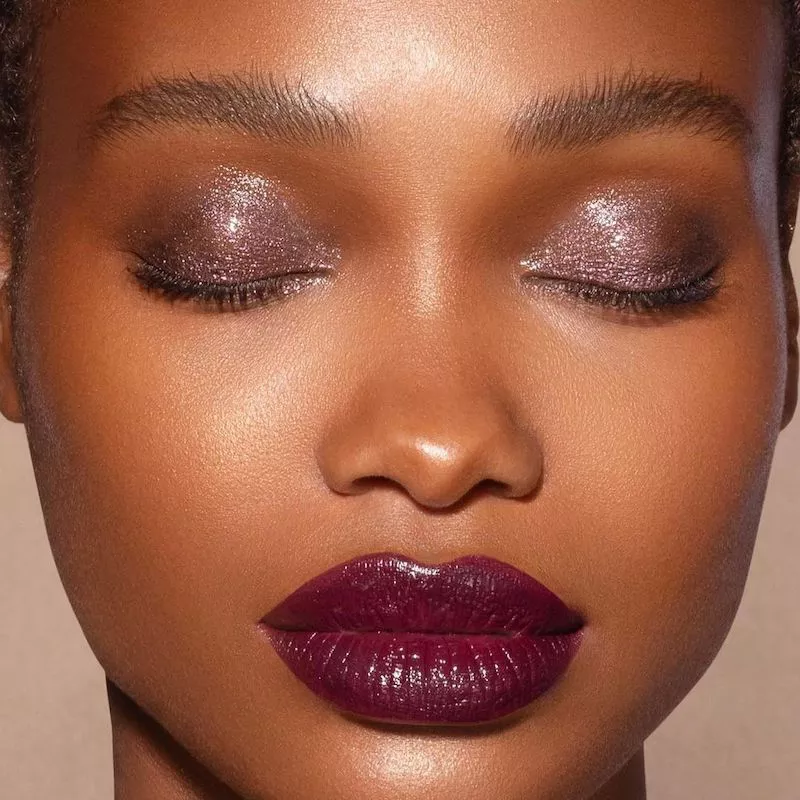 Model with purple glossy eyeshadow and burgundy lipstick