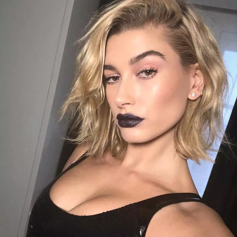 Hailey Bieber wears a radiant makeup look with black lipstick and a blonde long bob hairstyle