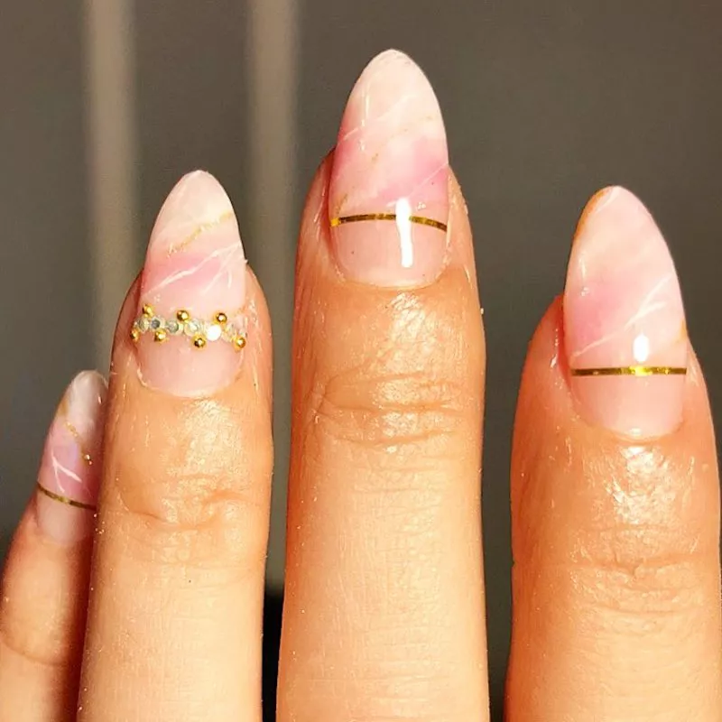 Almond-shaped nails with rose quartz design and gold detailing