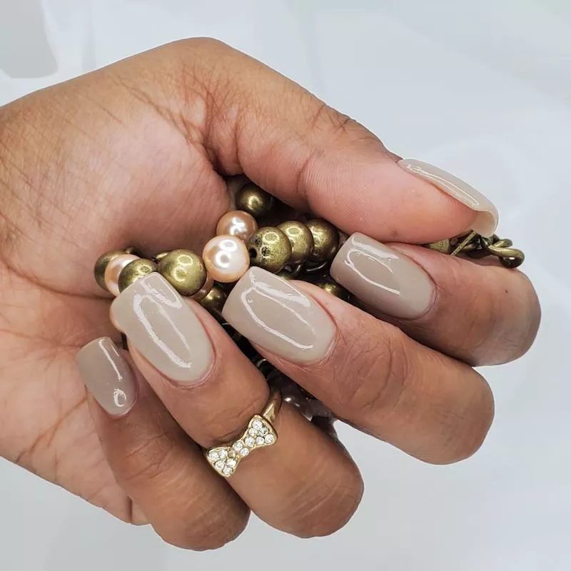 Neutral dip powder nails with bow ring holding pearlescent beads