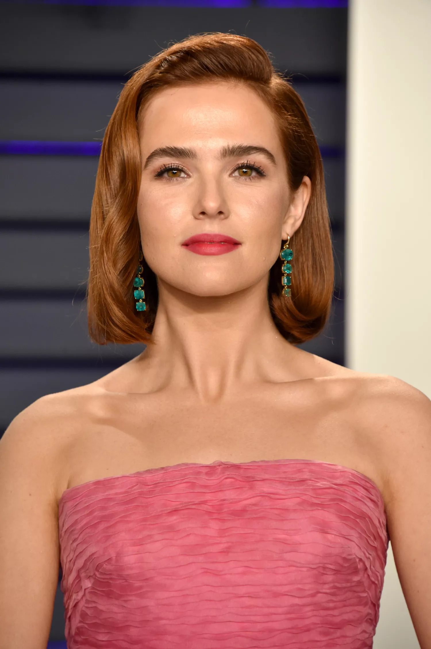 Zoey Dutch posing on the red carpet in a pink gown at the 2019 Vanity Fair oscar party