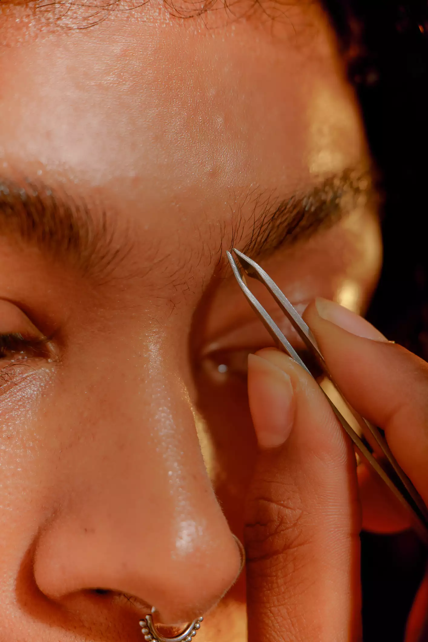 Close up of woman plucking eyebrows