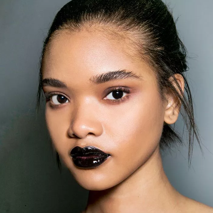 Model with glossy black lipstick and radiant skin