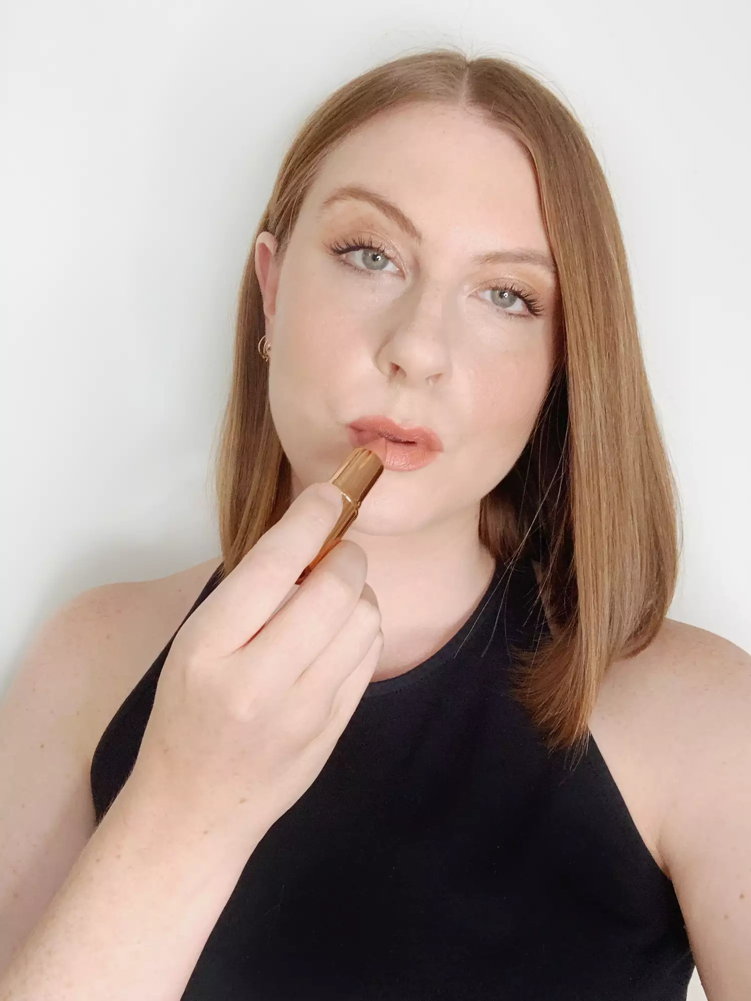 Ashley Rebecca applying lipstick for overlined lips look