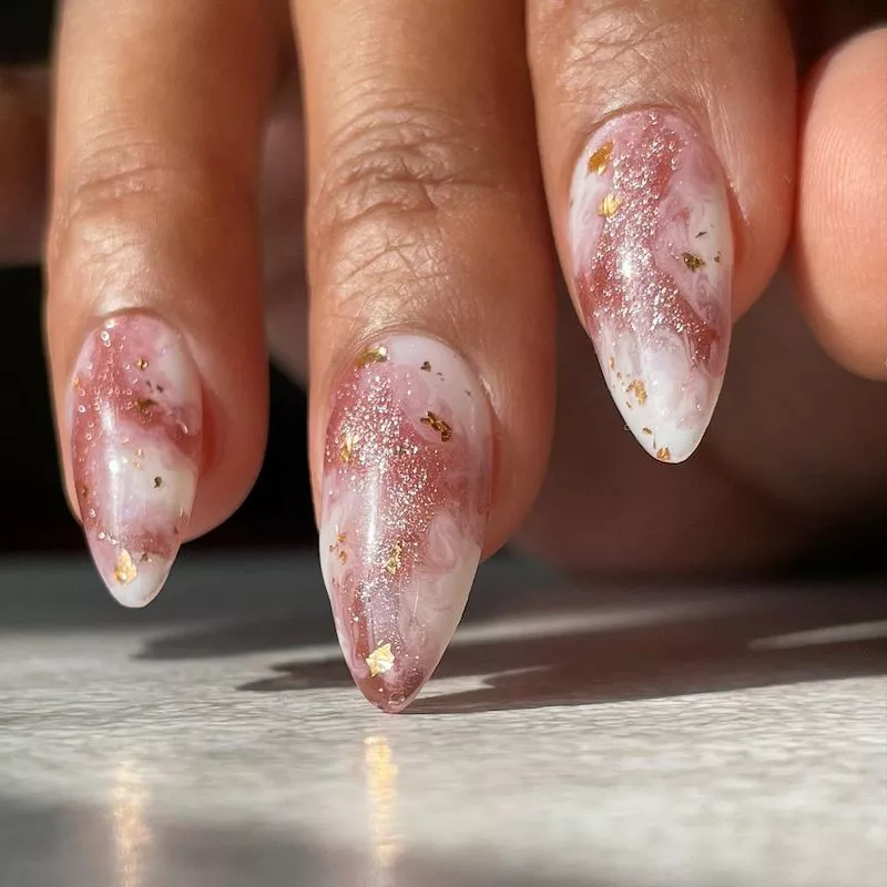 Pink marble manicure with glitter and gold flecks