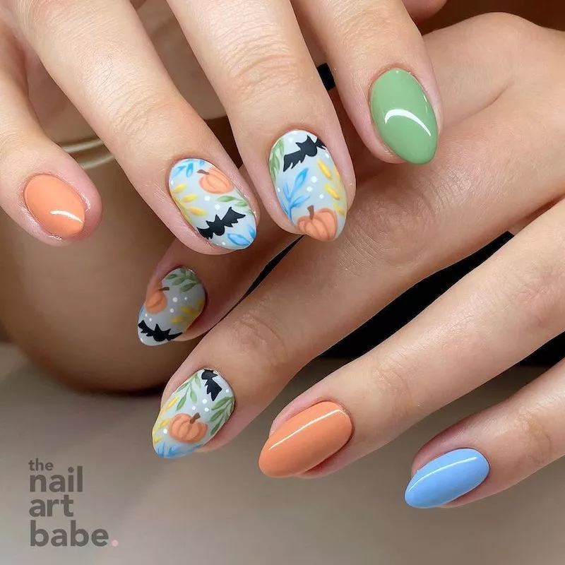 Pastel green, orange, and blue manicure with bat and pumpkin design accent nails
