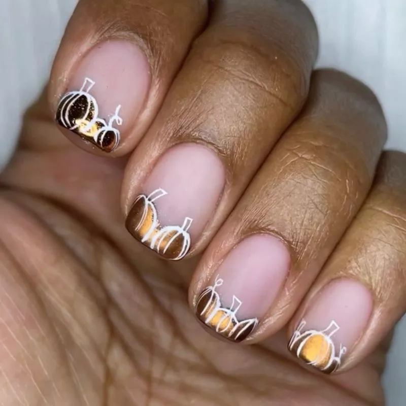 Gold and white pumpkin nail design on tip of manicure