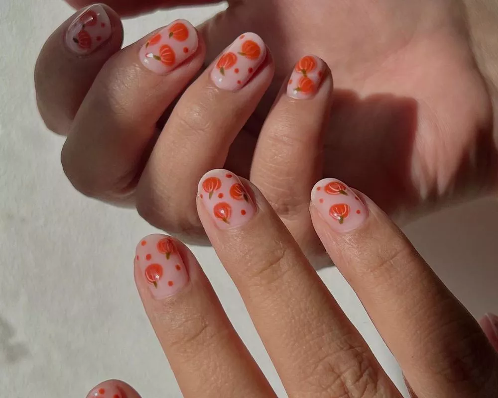 Neutral manicure with orange pumpkin nail designs and polka dots