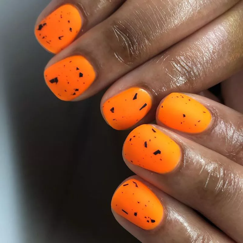Neon orange manicure with black speckled design