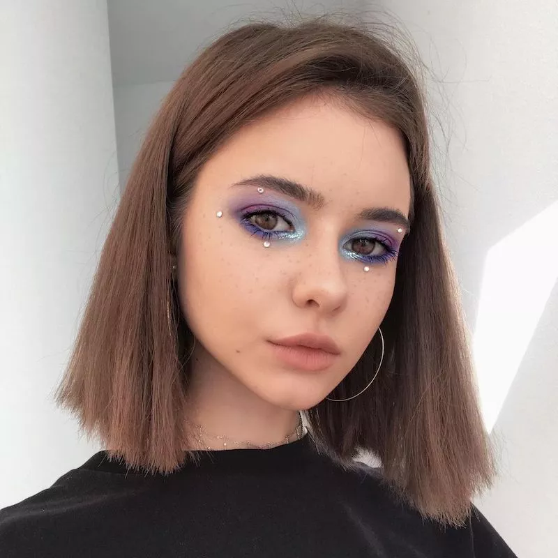 Makeup artist with blue and purple gradient eye makeup with pearls