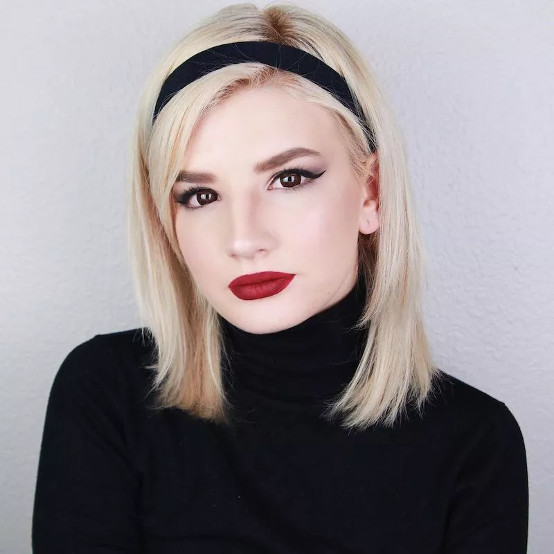Makeup artist wears a Sabrina the Teenage Witch-inspired hair and makeup look and costume